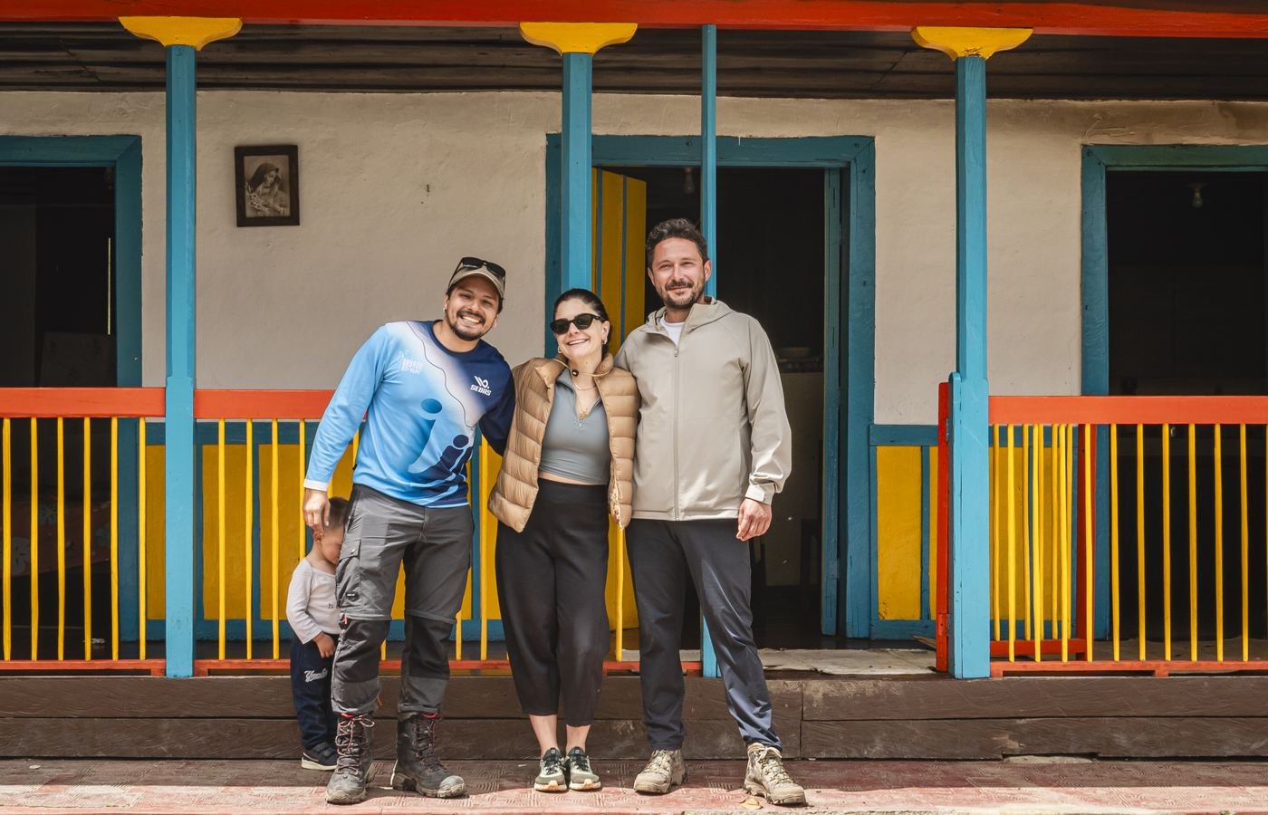Guía de Cayana con viajeros frente a una casa campesina de colores